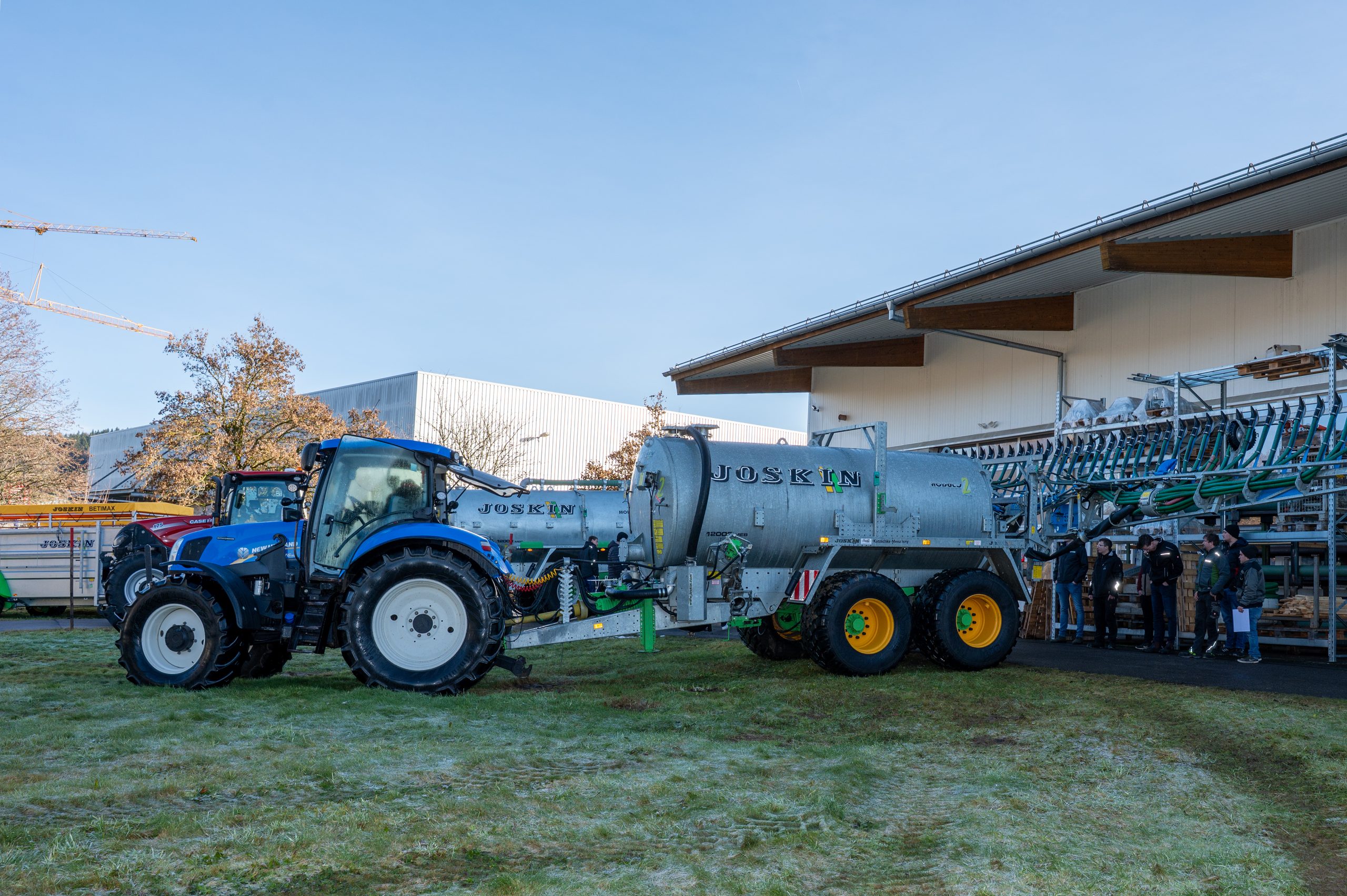 Traktor mit JOSKIN-Güllefass und ausgeklapptem Verteiler an einem frostigen Wintertag