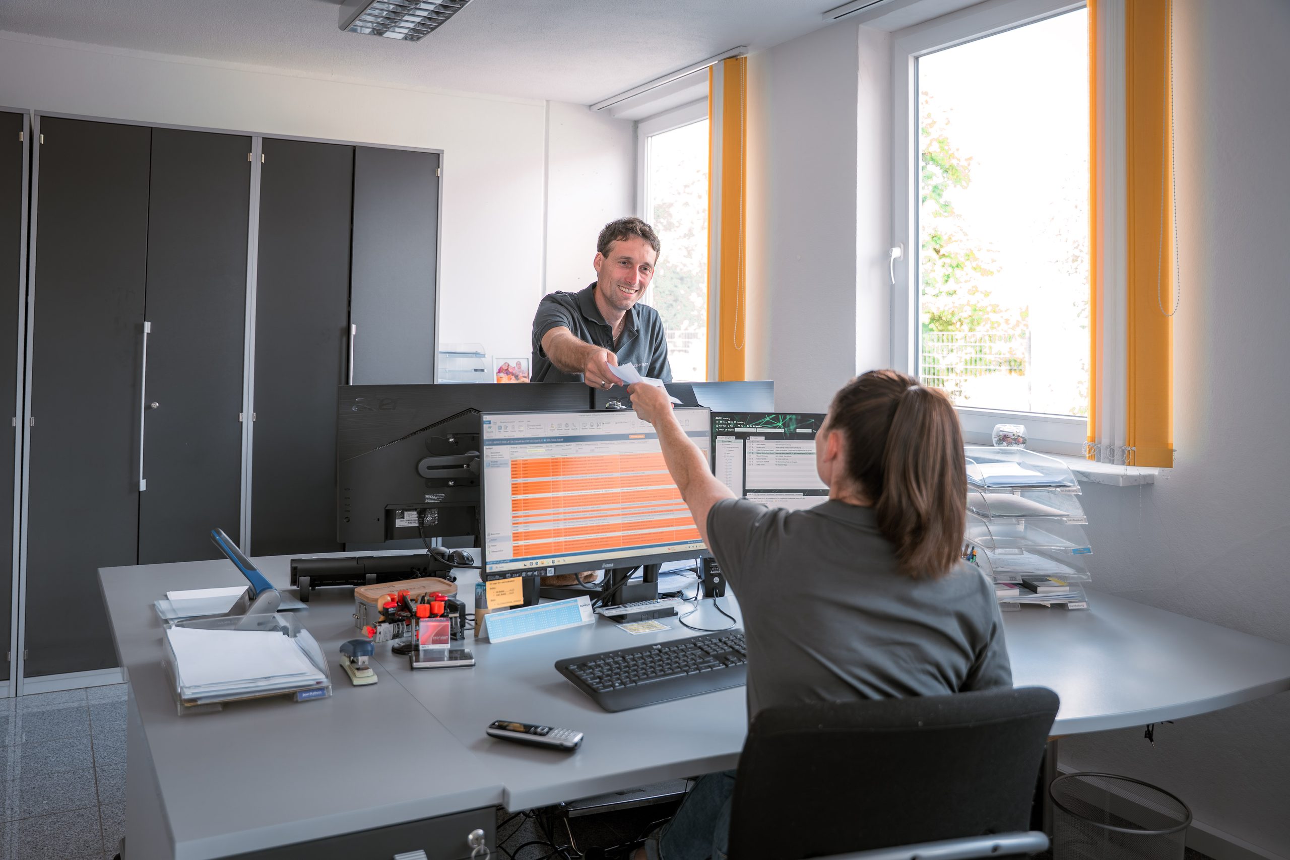 Übergabe eines Belegs am Schreibtisch im Büro von Katzschke-Menz