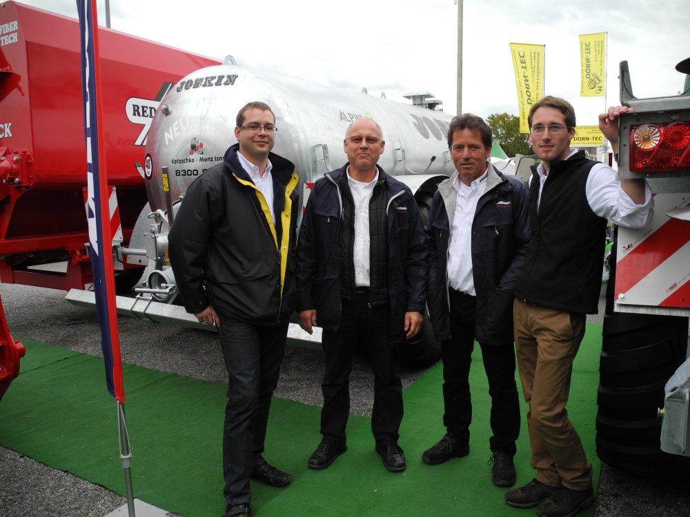 Vier Männer vor Güllefässern und REDROCK-Technik am Messestand