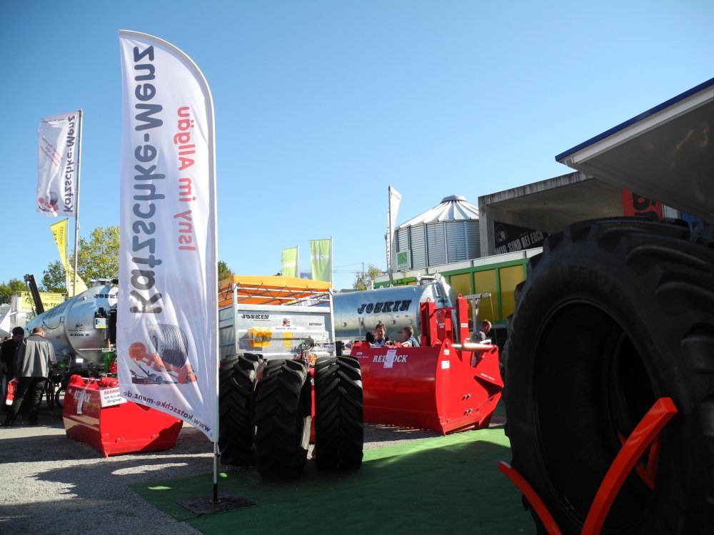 Fahne von Katzschke-Menz vor Güllefässern, Reifen und roter Technik am Messestand