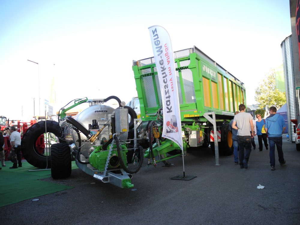 Güllefass mit Verteilertechnik vor einem grünen Ladewagen am Messestand