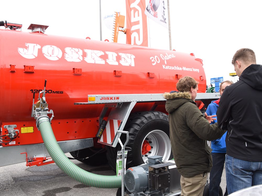 Rotes JOSKIN-Güllefass mit Pumpe am Messestand, daneben Besucher