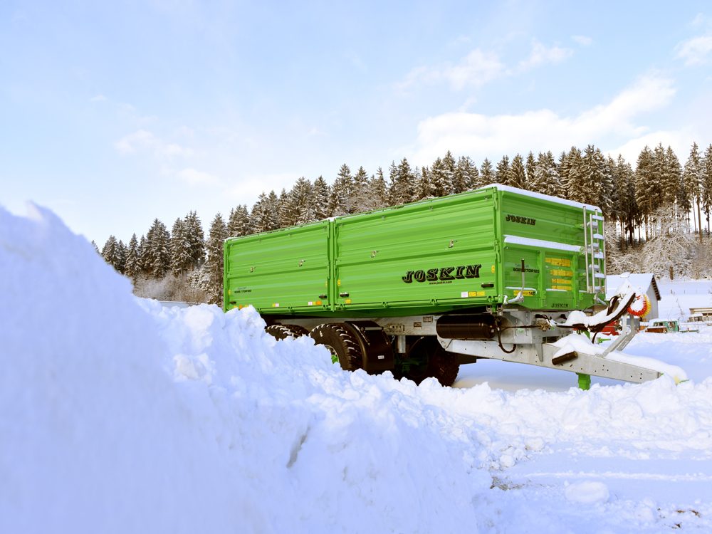 Grüner JOSKIN-Kipper hinter einem Schneewall