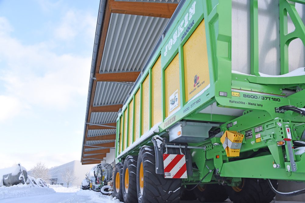 Grüner JOSKIN-Ladewagen unter dem Vordach der Halle